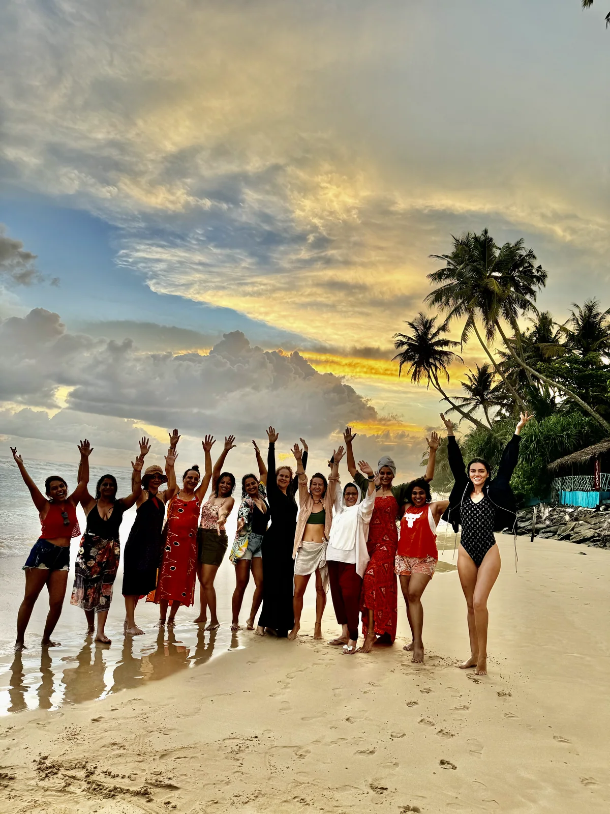Retreat group celebrating together on a beach at sunset